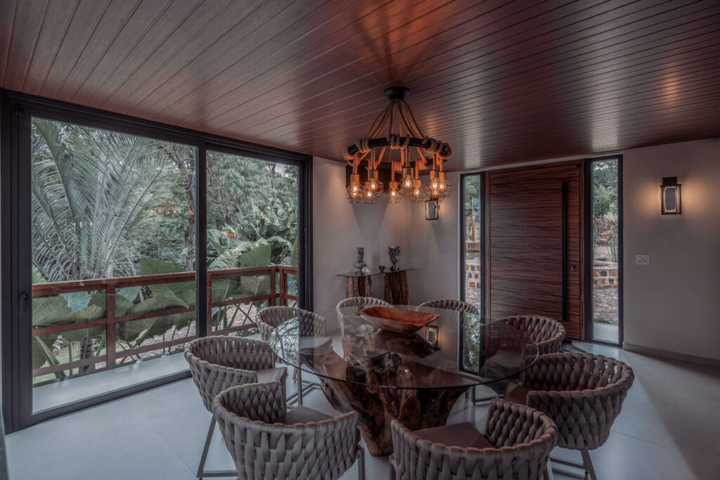 Sala de jantar com madeira, vidro e vista para a vegetação na Residência Âmago